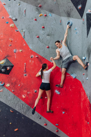 Strong man trying to lift climbing girl. Hand with tense muscles. Man attempting to help woman...