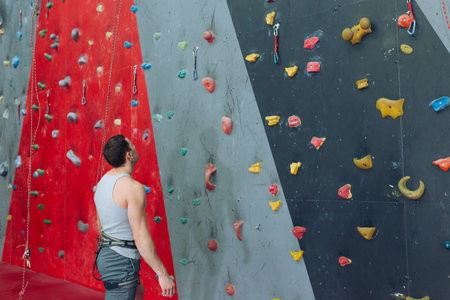 young attractive guy looking at the artificial rock wall and thinking about the route. rare view ....