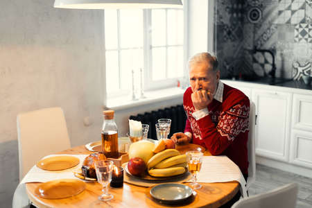 unhappy old man is waiting for his relatives. gey-haired man is celebrating Chritmas alone.の写真素材