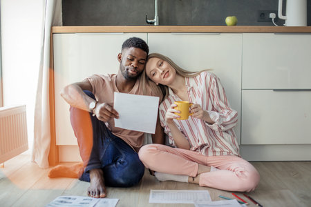 Interracial young couple of entepreneurs sharing ideas about new small business project, working at...