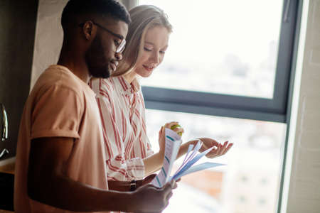 Interracial young couple of entepreneurs sharing ideas about new small business project, working at home with documents, planning new marketing concept, Small or family business collaboration conceptの写真素材