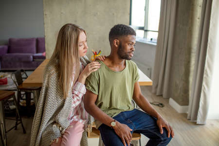 Support Concept. Young blonde womantrying to comfort her upset african friend who has just lost his job.の写真素材