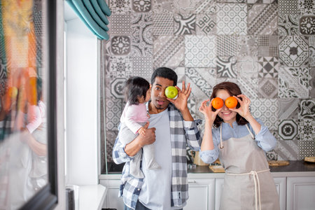 funny young family using fruit like glasses and posing to the camera. close up photo, craziness,...
