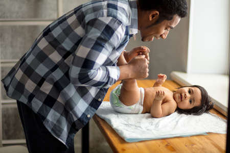 Young handsome Afro father is playing with his baby girl, close up side view photo.happiness, free time, spare timeの写真素材