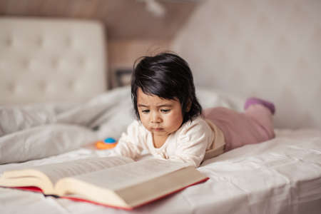 little cute girl enjoys reading a book. close up photo free time, hobby, lifestyle, childhoodの写真素材