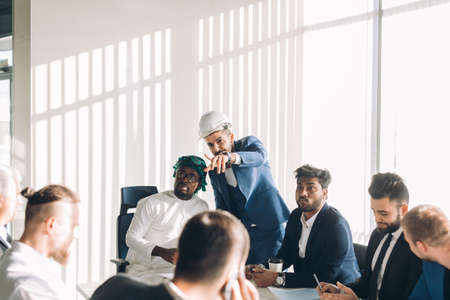 Multiracial group of experts headed by Arab leader, dressed in national white wear, analyzing business result and discussing profit.の写真素材