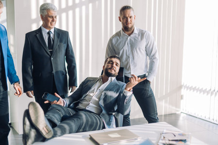 Happy company male ceo, founder, owner, boss or board member lounged in a chair with his assistants...