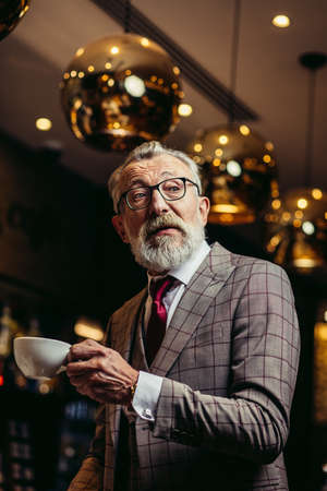 Portrait of surprised senior businessman in drinking coffee near bar counter at elite gentlemen s clubの写真素材