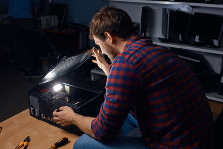 awesome happy man enjoying working with broken computers, favourite job. man has found the reason of broken PCの写真素材
