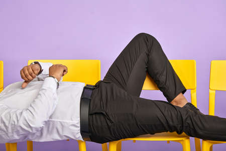 young man resting on chairs with crossed hands. Hands and legs close up and waiting for job interviewの写真素材