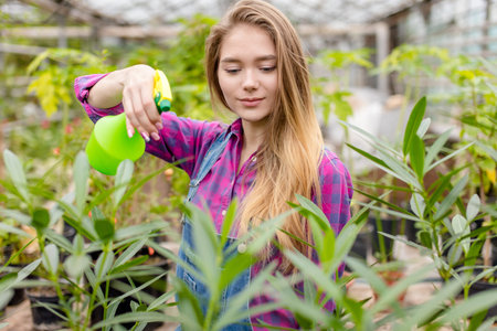 beautiful girl spraying pesticide on her flowers at greenhouse. close up photo. free time. hobbyの写真素材