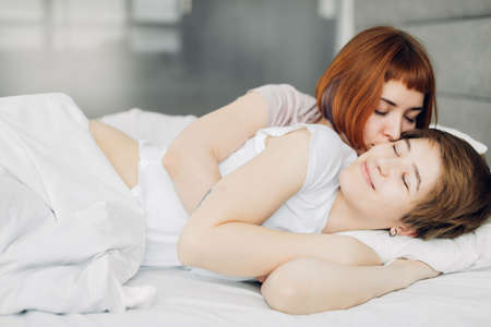 attractive red-haired girl waking her sister up. close up photo. love, amour, fondnessの写真素材