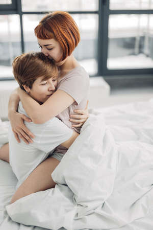 two pensive thoughtful lesbians are hugging at home. close up photo. copy spaceの写真素材
