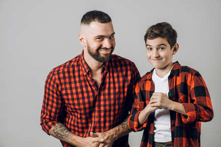 dad and a kid with a cunning plan. secret information. father and son have prepared a surprise for a mom. isolated grey background. studio shotの写真素材