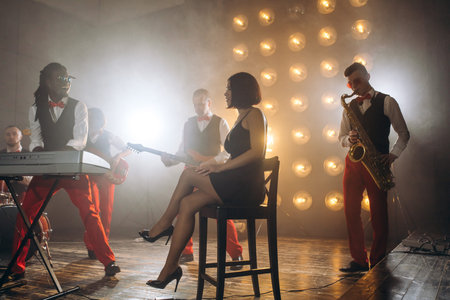 elegant girl in black dress controlling the rehaersal of a jazz group.