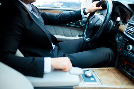 personal driver of business people sitting behind wheel of executive car, wearing tux....