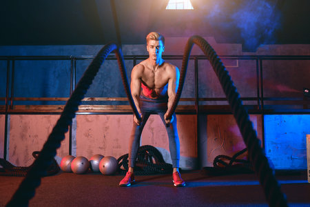 Male athlete stops doing boring cardio workouts and starts using the battle ropes to really crank it...