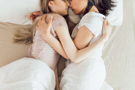 young lesbian couple embracing in the bed.top view cropped photo. free time, spare time. relationshipの写真素材