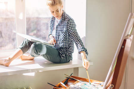 awesome pleasant girl choosing a brush for painting. close up photo. free time, spare timeの写真素材