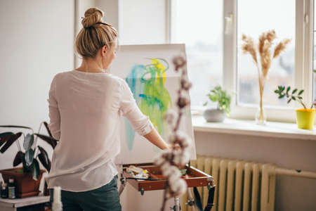 young creative girl having fun with paint and brush. close up back view photo. happy atmosphere in art classesの写真素材