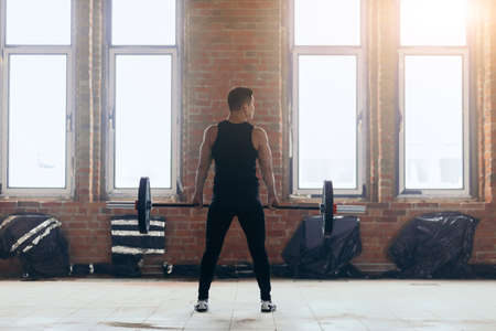 powerful guy pumping up muscles at gym. full length back view photo. sport activity. spare timeの写真素材