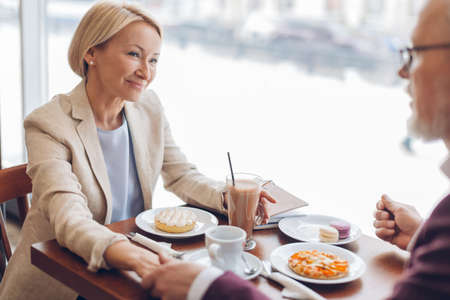 happy beautiful mature woman having a talk with her husband in the coffee shop. close up side view photoの写真素材