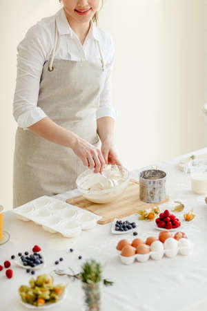 young pleasant woman mixing the dough with a spoon, close up cropped photo. side viewの写真素材