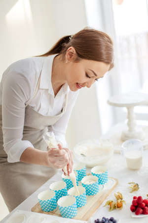 attractive smiling girl creating tasty treats for any occasion, close up side view photo.cupcake recipeの写真素材