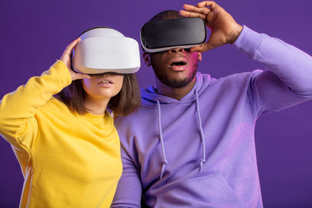 Surprised excited open mouthed multiethnic diverse people wear head mounted displays playing video...