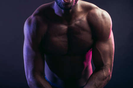 African American male athlete posing at studio on dark background, demonstrating muscular body, promoting fitness, sports, healthy lifestyle and bodybuilder conceptの写真素材