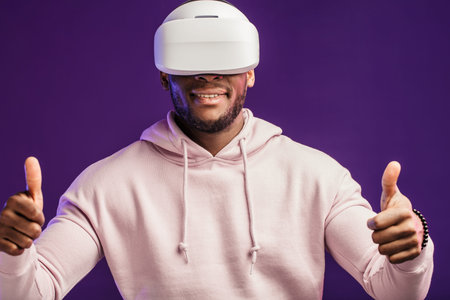 African American guy in white hoodie is playing a virtual reality game using head-mounted display,...