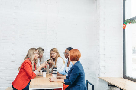 Team work process. Multiracial group of young women collaborating in open space office. Red-haired...