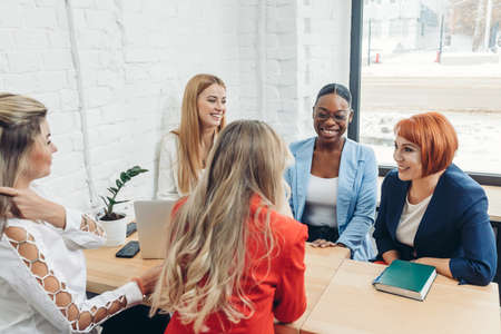 Women Team work and team building concept. Positive start up female partners in casual clothes discussing the ideas for new strategy of development at nice comfortable light officeの写真素材