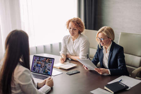 Two female human resources managers conducting job interview with woman applicant in office. Getting a new job conceptの写真素材