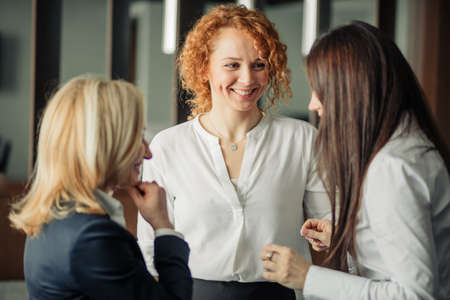 Three positive business women chatting in office lobby.の写真素材