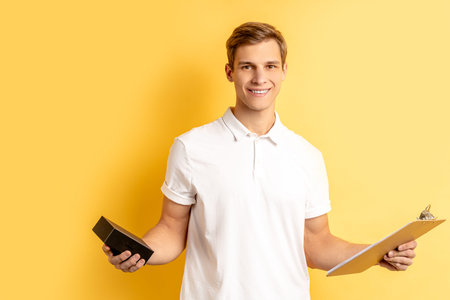 portrait of young caucasian delivery man in unifrom carrying things for customer, isolated over...