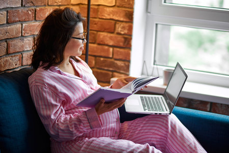 adorable peaceful pregnant woman working with laptop,wearing homie clothes. beautiful brunette with...