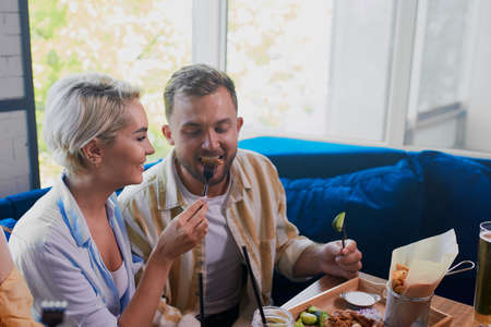 young caucasian couple have romantic time in cafe, beautiful lady treats her boyfriend with mealの写真素材