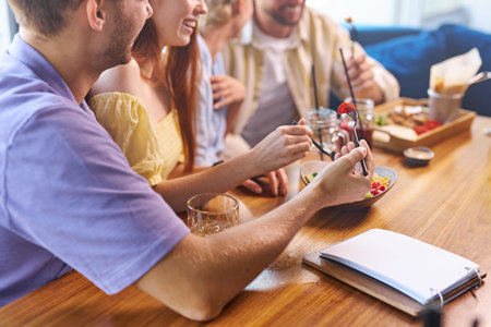 friends try delicious food in restaurant, have a great time together, smile and talk