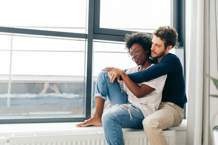 Romantic mixed race affectionate young newlyweds relax at modern hotel interior while vising foreign...