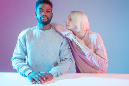 albino girl leaning on her Afro boyfriend while resting at the table, close up photo. isolated...