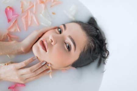 Close-up portrait of female face relaxing in milky white water, looking at camera