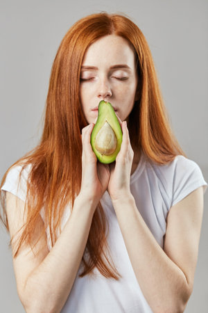 emotional girl holding half of avocado near the mouth, lips. close up photo. beauty .