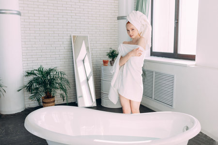 Purity, Tenderness and Sensuality. Backside portrait of fit slim woman with white towel standing...