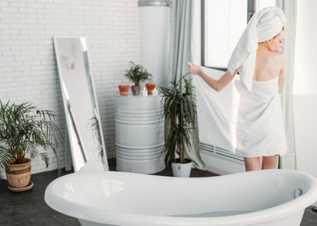 Purity, Tenderness and Sensuality. Backside portrait of fit slim woman with white towel standing...