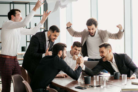 cheerful caucasian business people in office, happy after getting news about their winning in business project, sucessful business crew celebrate in office, dressed in formal wearの写真素材