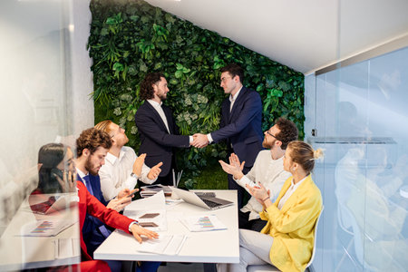 young successful business people signed an agreement in office, shaking hands in the presence of...