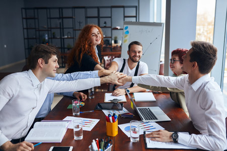 Solving problems as one team. Caucasian young team of male and female working together while sitting...
