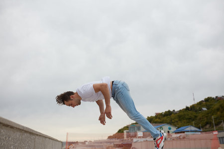 young man going to fall during performing a stunt, side view full length photo.