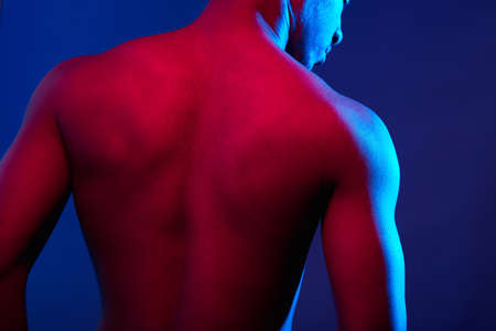 Close up of sports male muscular naked back isolated on dark violet backgroundの写真素材